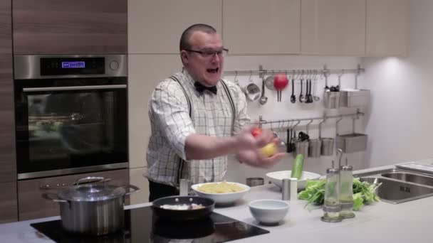 De man in de keuken jongleert groenten — Stockvideo