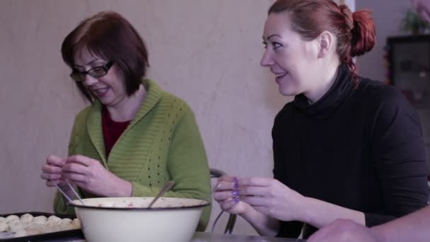 Women mold dumplings at the kitchen table — Stock Video