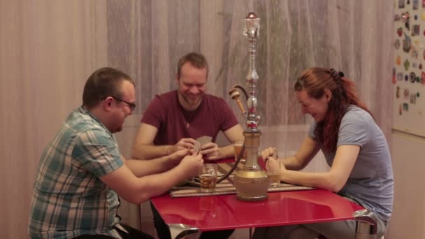 Tři přátelé kouřit vodní dýmku a hrací karty — Stock video
