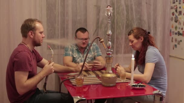 Двоє чоловіків і жінка курить шишу і розмовляє — стокове відео