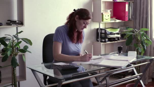 Vrouw ondertekent documenten aan de tafel — Stockvideo