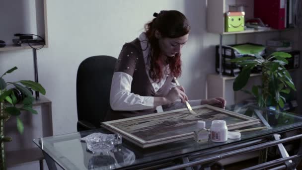 Vrouw met een penseel schildert een beeld-vernis — Stockvideo