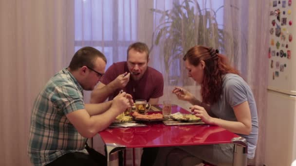 Amigos se sientan a la mesa y la cena — Vídeos de Stock