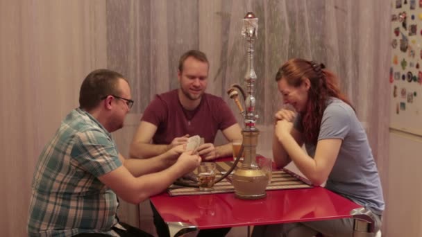 Drie mensen roken shisha en speelkaarten — Stockvideo