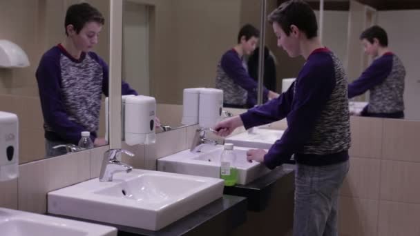Подросток моет руки в раковине. — стоковое видео