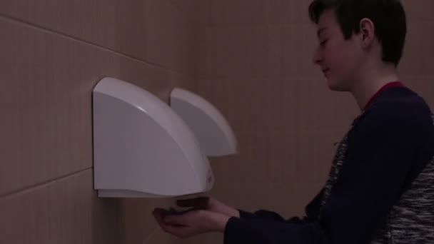 Tiener droge handen op handdroger in toilet — Stockvideo