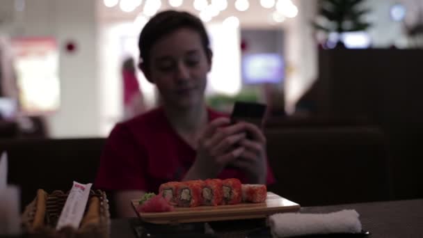 Подросток сидит в суши-кафе — стоковое видео
