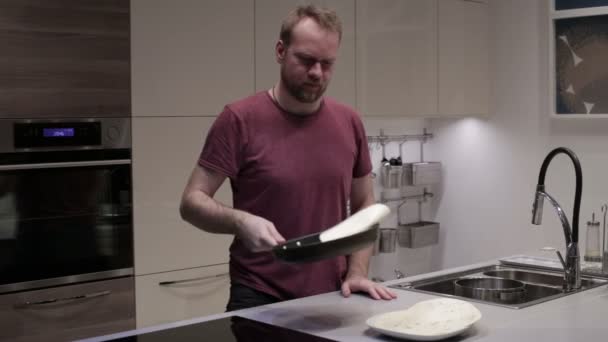 Человек переворачивает блины в сковородке — стоковое видео