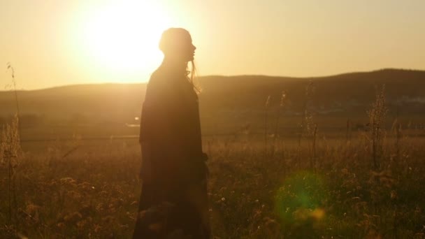 Vacker flicka vid solnedgången i strålar från solen — Stockvideo