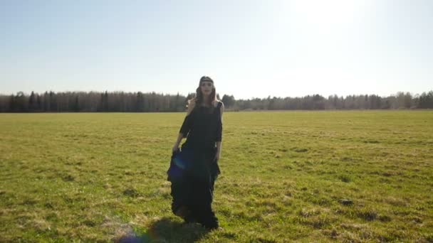 Krásná dívka v dlouhých černých šatech chodí na poli — Stock video