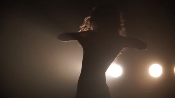 Silhouette d'une fille dansant sur les lumières de fond 