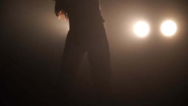 Silhouette d'une fille dansant passionnément sur fond de lumières 