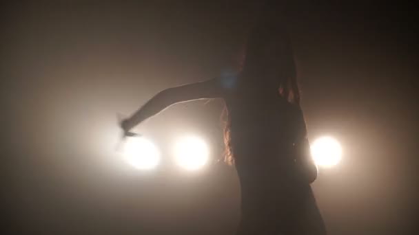 Silhouette d'une fille dansant passionnément sur fond de lumières 