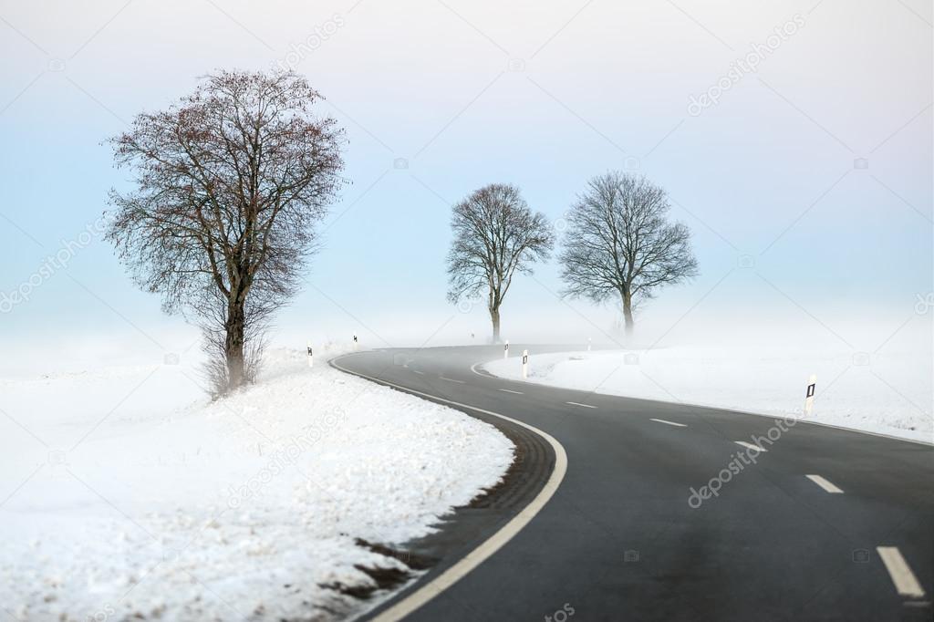 Black winding road in white winter landscape