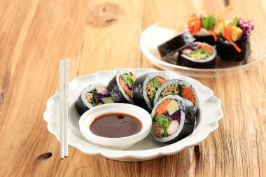 Kore usulü Gimbap, Pirinç, Havuç, Sosis, Yengeç Çubuğu, Yumurta, Balık keki ve Yosun Laver ile sarılmış. Baharatlı sos ile servis edilir. Tahta Masa 'da