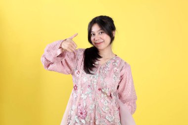 Endonezyalı Pembe Kebaya Giyen, Sarı Arkaplan 'da Başparmakları Yukarı Doğru Hareketli Genç Kadın