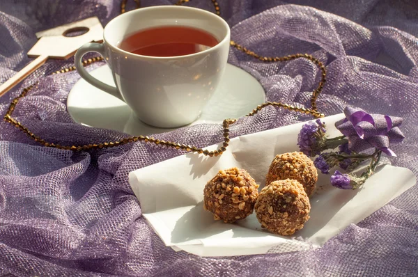 Uma composição arejada ensolarada com uma xícara de chá e doces de chocolate — Fotografia de Stock