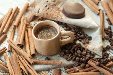 El yapımı çanak çömlek Kupası ile bir kompozisyon kahve, tarçın stickss, kahve çekirdekleri, toz kakao ve çikolata şeker