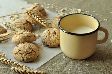 Bir rustik ahşap plaka, metal bir fincan süt ve kulakları ev yapımı bisküvi fotoğraf tahıl ile tarz