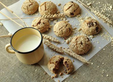 Bir rustik ahşap plaka, metal bir fincan süt ve kulakları ev yapımı bisküvi fotoğraf tahıl ile tarz