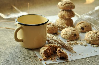 Bir rustik ahşap plaka, metal bir fincan süt ve kulakları ev yapımı bisküvi fotoğraf tahıl ile tarz