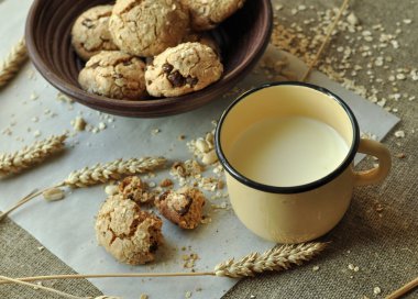 Bir rustik ahşap plaka, metal bir fincan süt ve kulakları ev yapımı bisküvi fotoğraf tahıl ile tarz