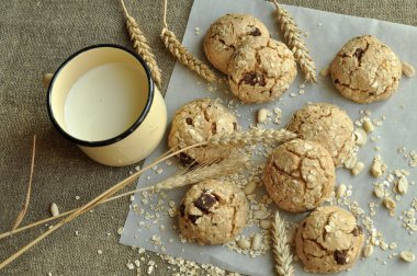Bir rustik ahşap plaka, metal bir fincan süt ve kulakları ev yapımı bisküvi fotoğraf tahıl ile tarz