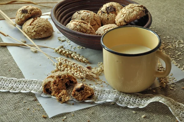 Bir rustik ahşap plaka, metal bir fincan süt ve kulakları ev yapımı bisküvi fotoğraf tahıl ile tarz