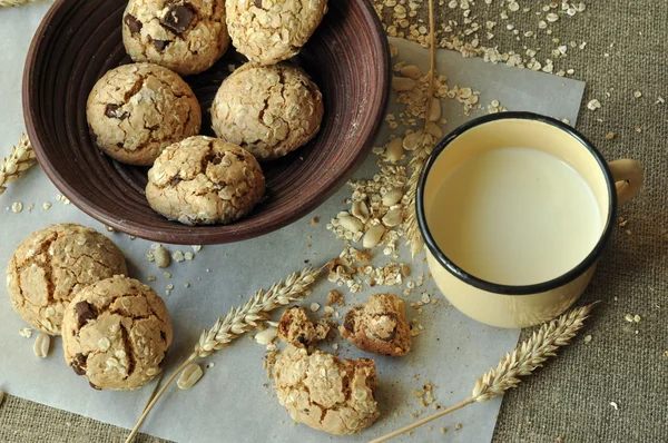Bir rustik ahşap plaka, metal bir fincan süt ve kulakları ev yapımı bisküvi fotoğraf tahıl ile tarz