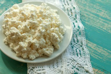 Süzme peynir bir ahşap yüzey üzerinde beyaz bir tabak içinde 