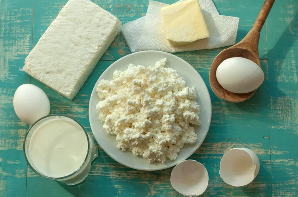 Produits du journal - lait, fromage cottage, beurre et œufs - sur une surface en bois — Photo