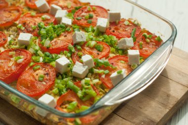 Beyaz peynir ve bir ahşap yüzeyde bir cam tabak içinde kesilmiş yeşil ile pişmiş sebze - kabak, havuç ve domates- 