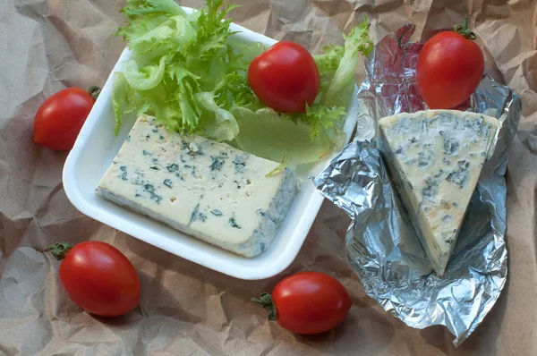 A package of food to take away including blue cheese, cherry tomatoes and fresh salad leaves
