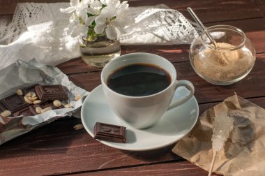 Bir kompozisyon ile bir fincan kahve, çikolata ve bir elma ağacı çiçek açan bir dal