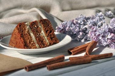 Bir çikolatalı kek, kağıt ve kalem, Lila çiçek ve bir kolye parçası ile bir kompozisyon