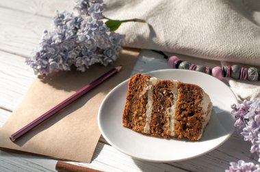 Bir çikolatalı kek, kağıt ve kalem, Lila çiçek ve bir kolye parçası ile bir kompozisyon