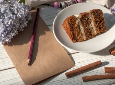 Bir çikolatalı kek, kağıt ve kalem, Lila çiçek ve bir kolye parçası ile bir kompozisyon