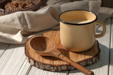 Süt, bir tahta kaşık ve bir rustik ahşap yüzeyde bir çanak çömlek kapta haşlanmış buğday tahıl ile metal bir kupa keten peçete ile dekore edilmiştir. 