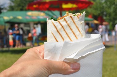 Bir ızgara pide rulo et ve sebze ile tutan bir kadın eli