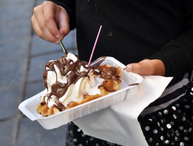 Waffle ile krema ve çikolata küçük bir kızın elinde; kentsel bir fotoğraf