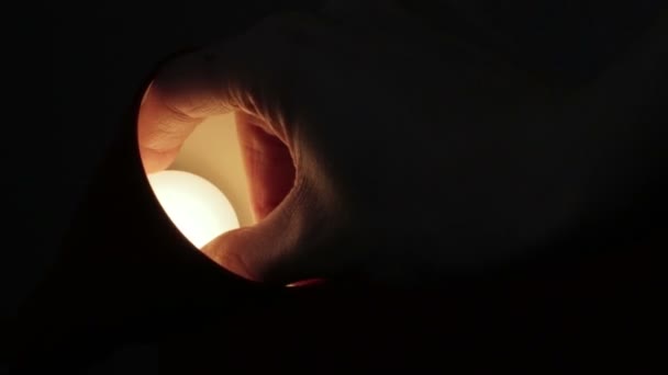Schrauben der Glühbirne in einer Tischlampe im Dunkeln — Stockvideo