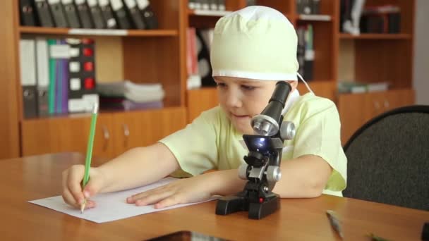 Маленький мальчик с микроскопом в исследовательской лаборатории — стоковое видео