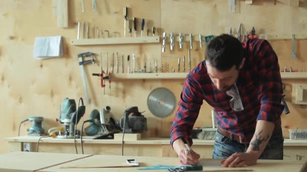 Carpinteiro desenha o projeto em uma oficina de carpintaria — Vídeo de Stock