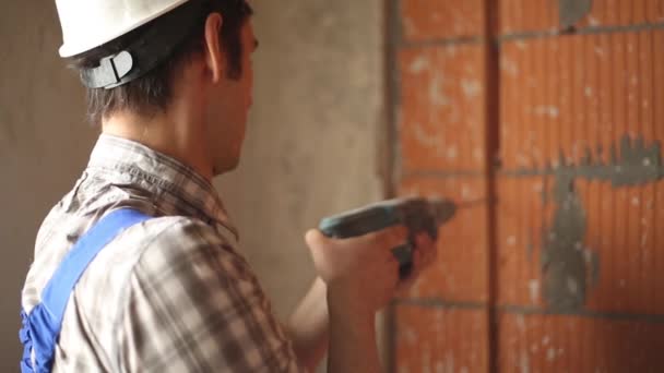 Arbetaren borrar hål i vägg — Stockvideo