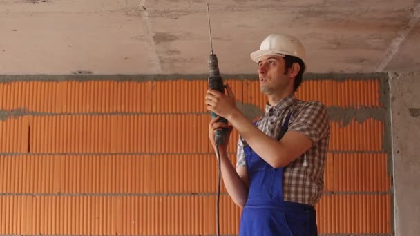 Bouwer in een helm is het boren van het plafond — Stockvideo