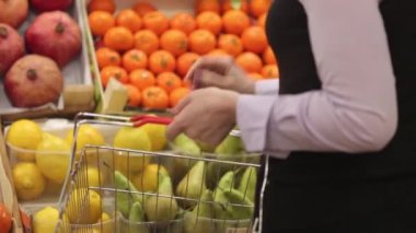 Kadın bir alışveriş sepeti ile meyve mağaza alışveriş yapar