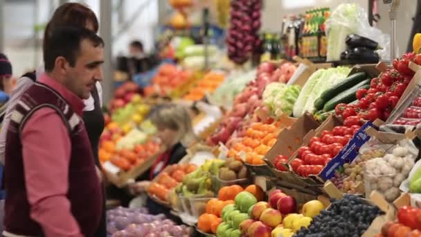 O vendedor ajuda o comprador a escolher frutas e legumes — Vídeo de Stock