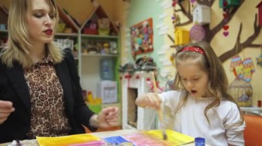 Öğretmen boyamak için küçük kız yardımcı olur.