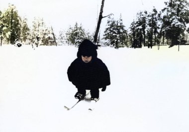 Kürklü ve şapkalı küçük bir çocuğun klasik portresi kayak yapmayı öğreniyor. 1970 'lerden kalma eski bir fotoğraf..