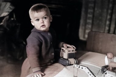 Oturma odasında oyuncak arabalarla oynayan küçük bir çocuğun klasik portresi. Şirin bir çocuğun komik fotoğrafı. 1970 'lerden kalma eski bir fotoğraf..